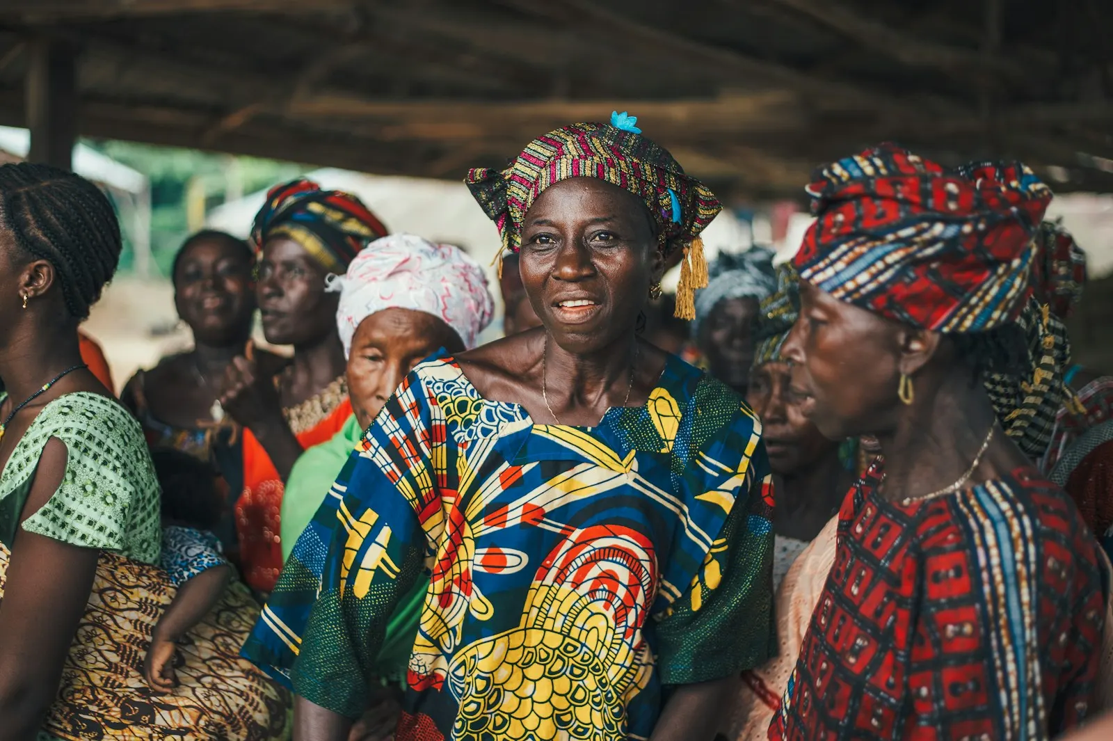 Women in bright printed dresses and headwraps gathered at a community meeting