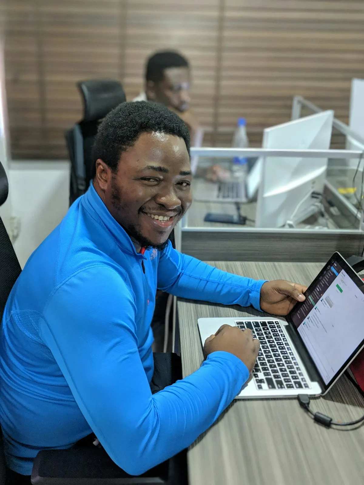 A smiling developer working on a laptop in an office
