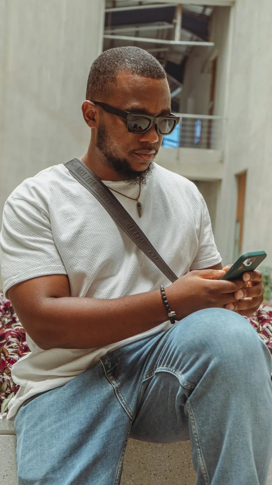A man sitting on a bench reading his phone