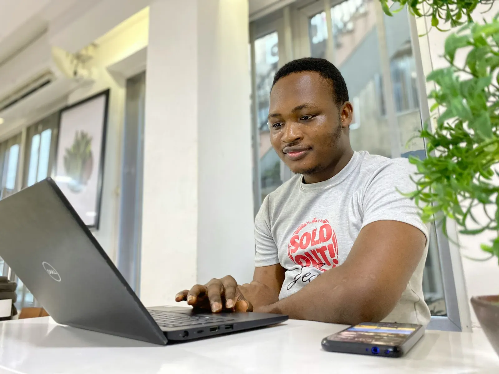 A young man working on a laptop in a bright office